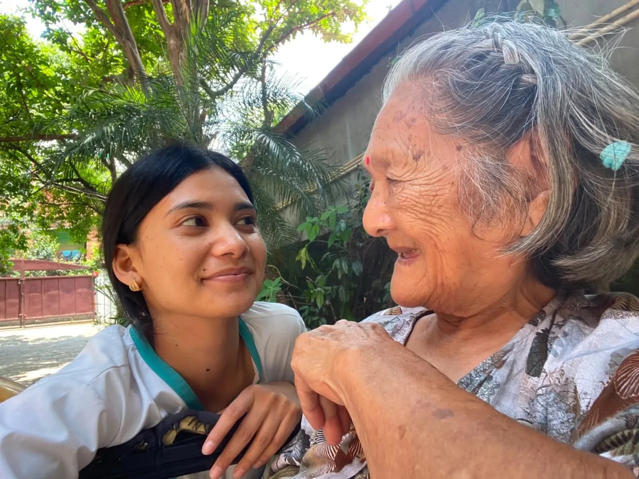 Aashirbad Care caregiver and an elderly woman sharing a warm moment outdoors